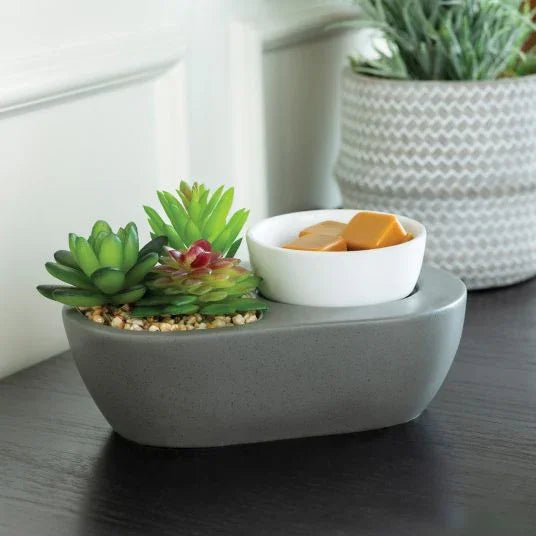 Modern wax melt warmer with artificial succulents in a gray planter on a table