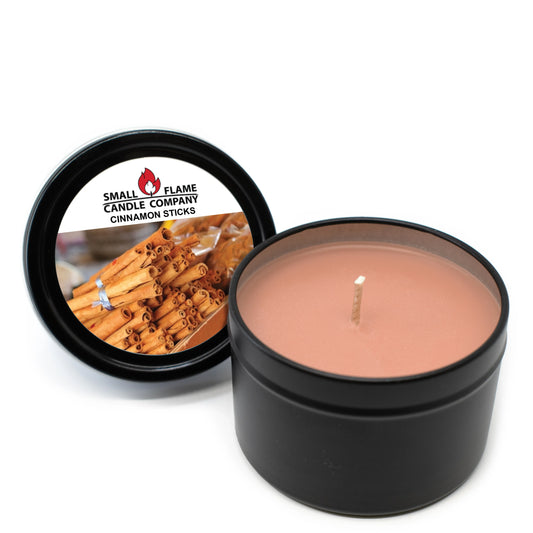 A round black tin from Small Flame Candle Company holds a hand-poured Cinnamon Sticks Candles and Melts made with natural coconut soy wax. The lid, set aside, features bundled cinnamon sticks and the product label.