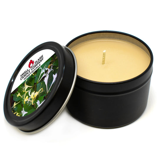A black tin Honeysuckle Candle by Small Flame Candle Company features beige coconut soy wax, a centered wick, and a lid decorated with floral art and the text “SMALL FLAME CANDLE COMPANY HONEYSUCKLE IVY.”.