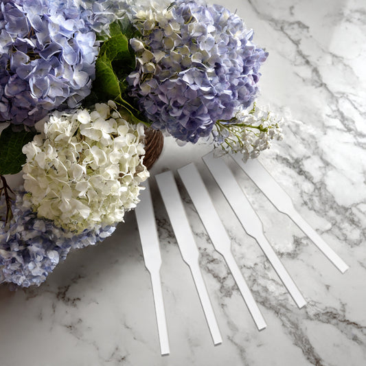 A bouquet of blue and white hydrangeas sits on marble beside five blank Fragrance Sampler scent tester strips from Small Flame Candle Company—an ideal way to discover your perfect scent before your next candle purchase.