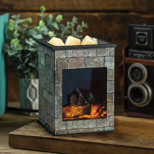 The Hearthstone Illumination, a fragrance warmer styled like a stone fireplace, sits on wood with yellow wax melts on top. A potted plant and vintage camera decorate the background.