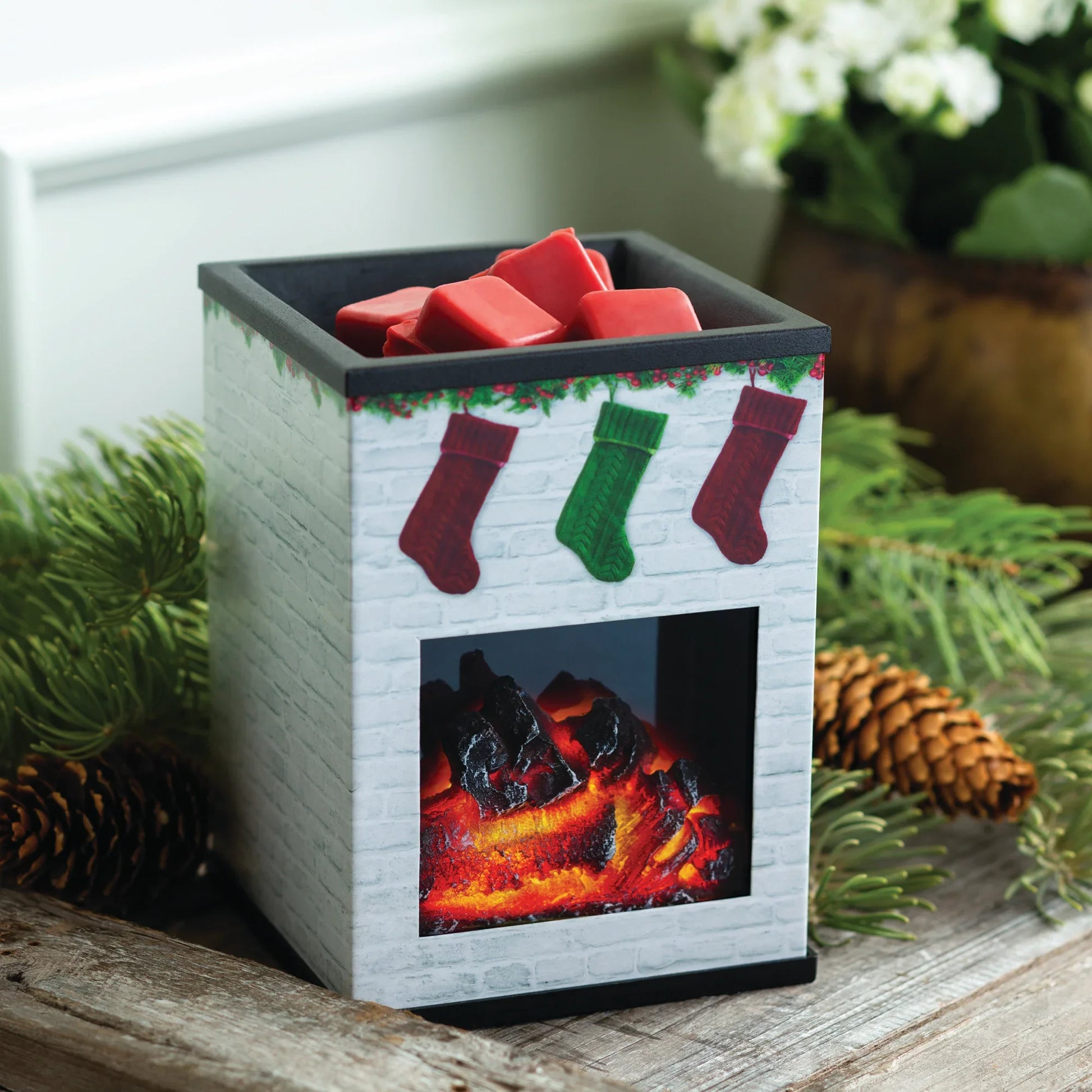 Holiday wax melt warmer shaped like a fireplace with red wax melts, pine and pinecones